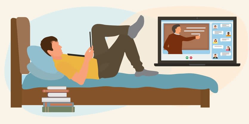 Student lies on bed and listens to lecture with teacher via laptop
